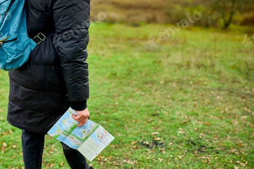 Preview: Close up of Traveler man with backpack with map in hand on a background of mountains river of nature