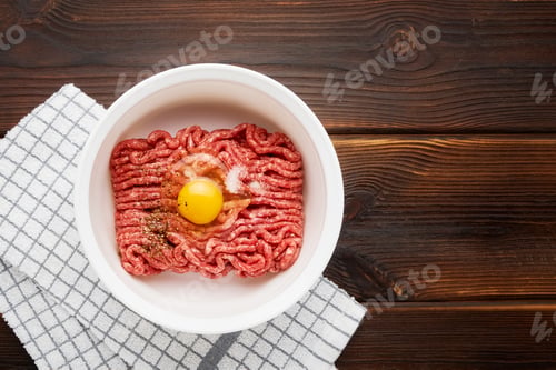 Preview: Raw ground beef or minced beef in a white bowl on wooden background. Top view, copy space