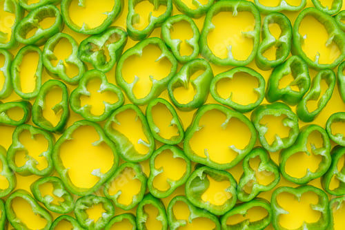 Preview: Top view of sliced green peppers on yellow background