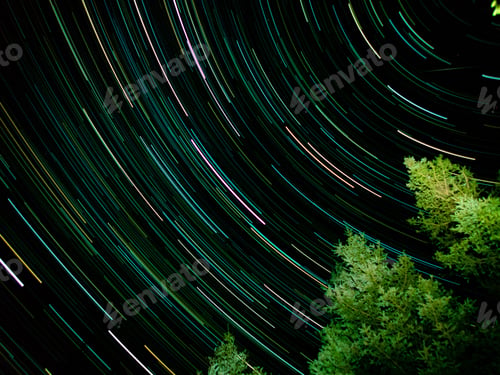Preview: :ong exposure of A night sky with a row of trees silhouetted against a star-studded backdrop