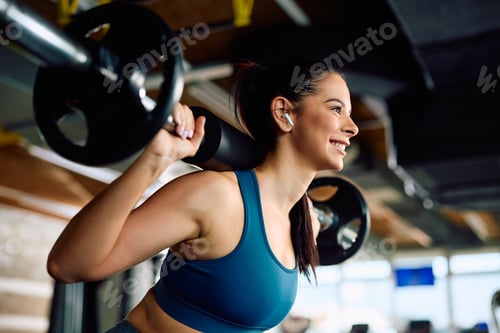 Preview: Happy female athlete having strength training in a gym.