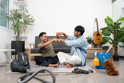 Preview: Two young men engaging in a playful moment while cleaning at home.