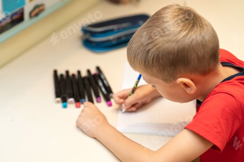 Preview: little boy doing homework at home at his desk. Back to school concept