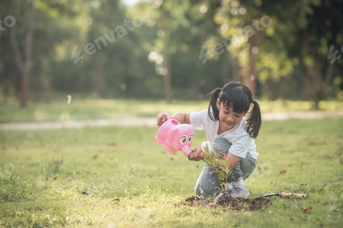 Preview: Asian little child girl pouring water on the trees. kid helps to care for the plants
