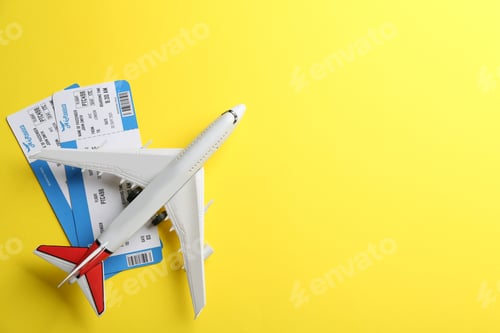 Preview: Toy airplane and tickets on yellow background, flat lay. Space for text