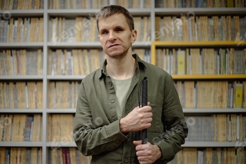 Preview: Portrait of Middle Aged Man Holding Cane Standing in Library Setting