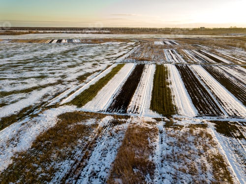 Preview: Top view of empty snowy fields patched landscape, dark horizon and bright sky