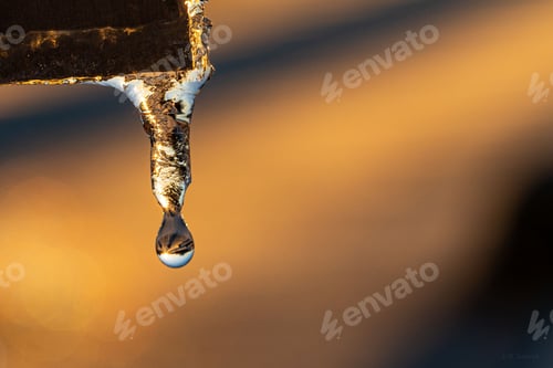 Preview: Close-up of a silver pipe with a melting icicle dripping from it