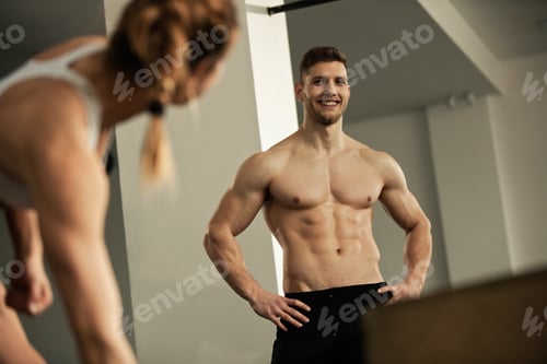 Preview: Happy muscular build man talking to woman during workout in a gym.
