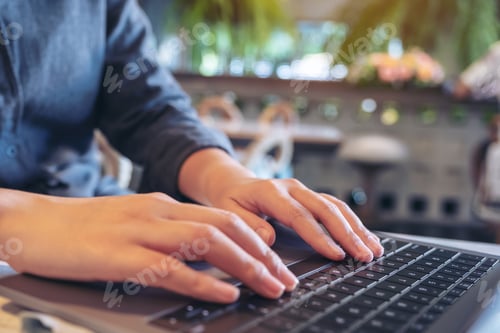 Preview: Closeup image of hands using and typing on laptop keyboard in cafe