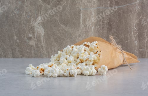 Preview: Crunchy popcorn spilling out of wrapping on marble background