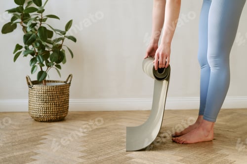 Preview: Young Adult Woman Rolling Yoga Mat after Home Workout Session