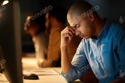 Preview: Cropped shot of a young businessman looking stressed out while working late in an office