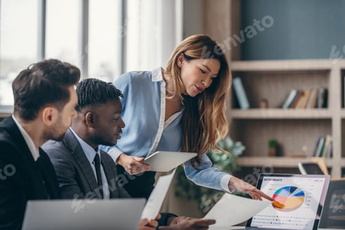 Preview: Three confident business people analyzing marketing data and using laptop while working in office