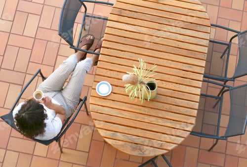 Preview: Young girl sitting on the terrace drinking coffee