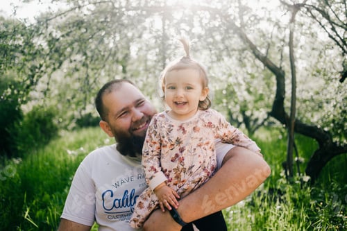 Preview: Father holding little daughter on the hands in the garden