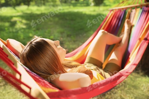 Preview: Young woman sleeping in comfortable hammock at green garden