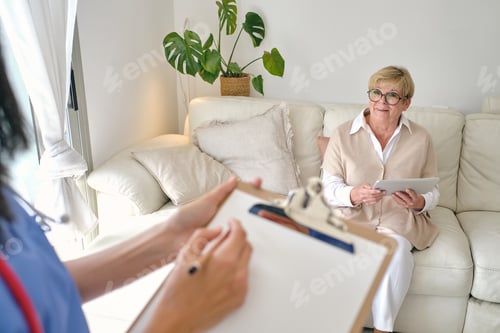 Preview: Crop physician interacting with elderly patient on sofa