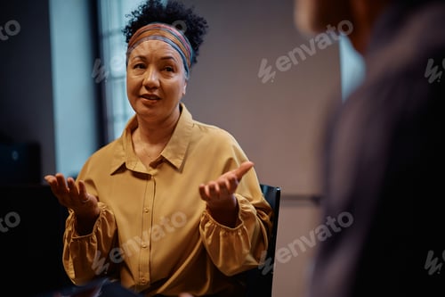 Preview: Mature woman talking about mental health issues during a group therapy session.