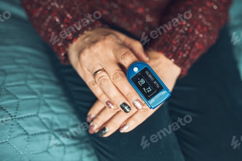 Preview: Woman measuring the degree of oxygen saturation of the blood and heart rate at home using pulse oxim
