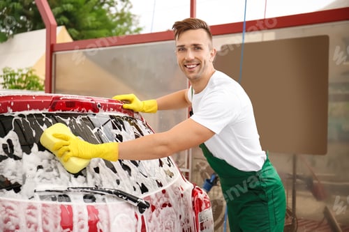 Preview: Male worker cleaning vehicle with sponge at car wash