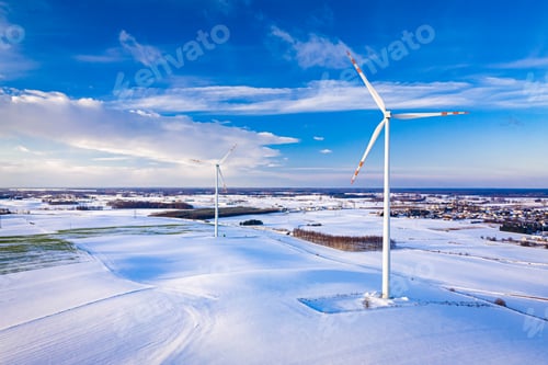 Preview: Beautiful snowy field and wind turbine at sunrise in winter