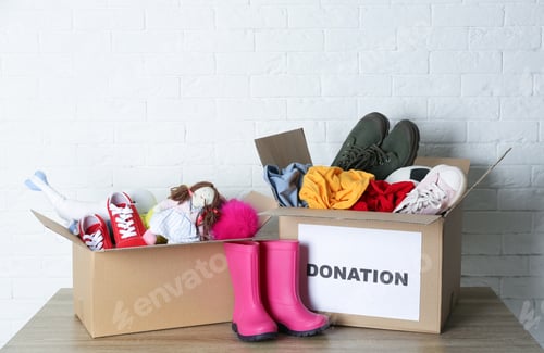 Preview: Carton boxes with donations on table near brick wall