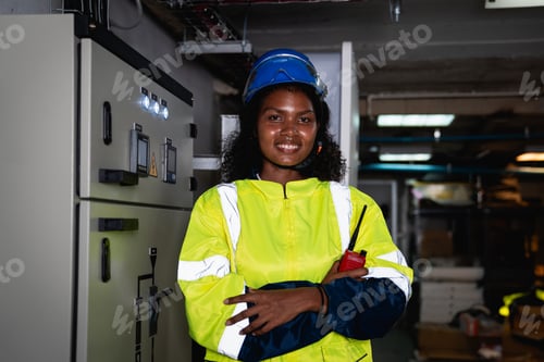 Preview: Technician in a yellow and blue safety vest is smiling and holding a walkie talkie