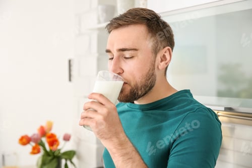 Preview: Young man drinking tasty milk at home