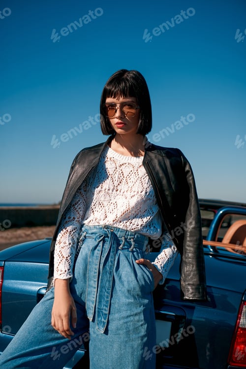 Preview: Close-up of young stylish woman with a haircut standing near roofless car