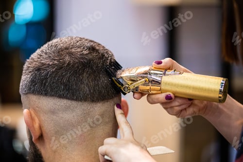 Preview: Barber woman cutting client hair to perfect shape using professional trimmer, close up view