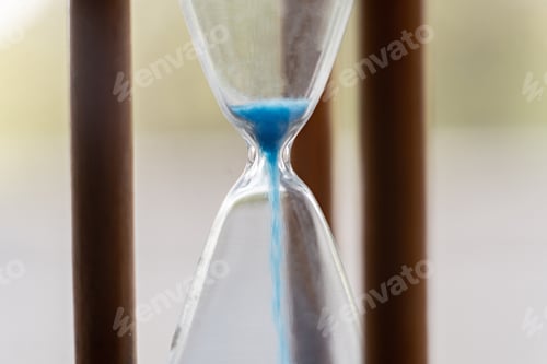 Preview: macro view of a blue sand pouring in the vintage old hourglass