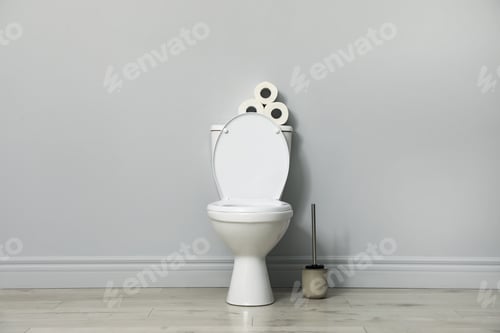 Preview: Ceramic toilet bowl, brush and paper near grey wall indoors