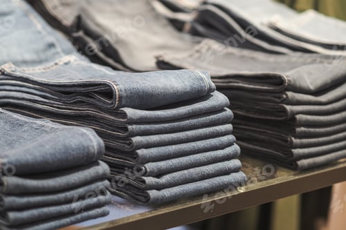 Preview: Folded jeans displayed on a store table for shopping