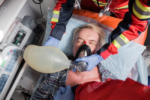 Preview: Top view of paramedics in latex gloves doing cardiopulmonary resuscitation to senior man