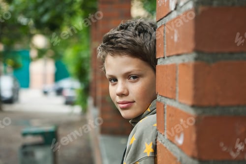 Preview: Germany, Berlin, Boy sitting behind brick wall