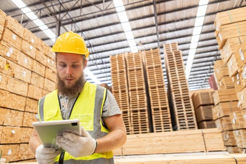 Preview: Worker Man with a bearded wearing safety uniform yellow hard hat using tablet working checking.