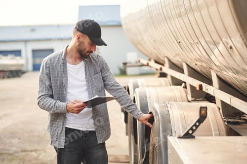 Preview: Black colored notepad in hands. Young truck driver in casual clothes