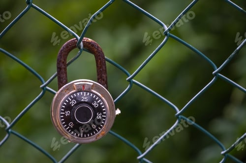Preview: Closeup shot of a rusty lock hanging from a wired fence