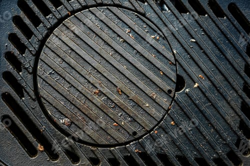 Preview: A black grill grate with a hole in the middle. The grate is dirty and has some food particles on it.