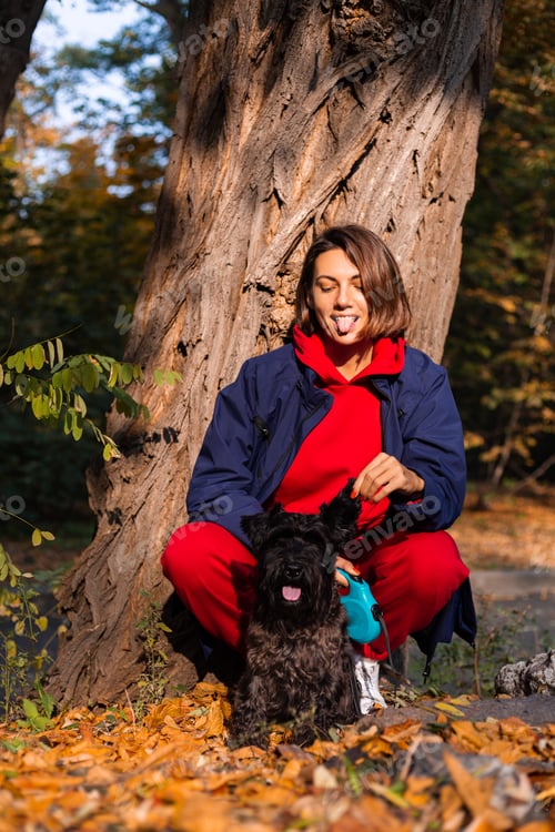 Preview: Early morning. Happy woman sleepy eyes with dog in park, autumn orange yellow colors.