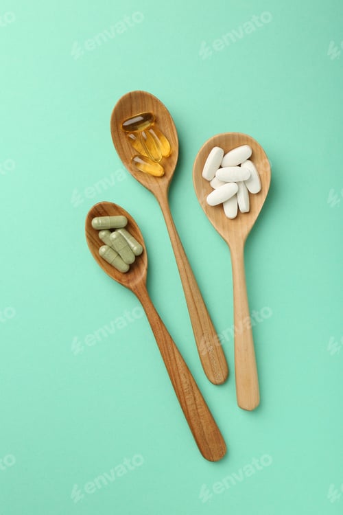Preview: Different vitamin capsules in spoons on turquoise background, flat lay