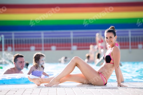 Preview: Mother, father and daughter in swimming pool. Sunny summer.
