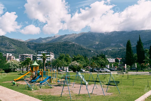 Visualização: Playground with swings and slides on a green lawn