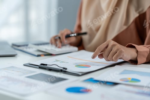 Preview: Motivated muslim businesswoman wearing hijab working on real estate project analyzing document data