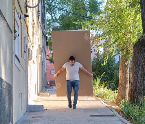 Preview: Young contractor carrying plasterboard sheets.