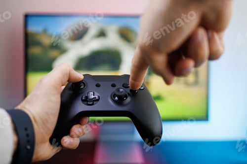 Preview: Finger presses the buttons of a game gamepad in the background of a monitor