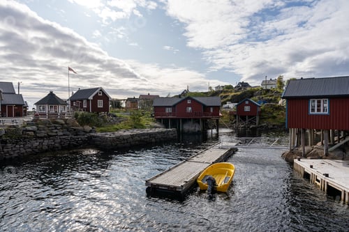 Preview: a yellow boat sits in a river next to houses and pier, A village Lofoten, Norway