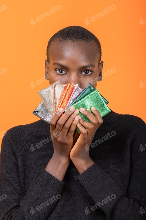 Preview: Black woman with colorful wallets isolated over orange background