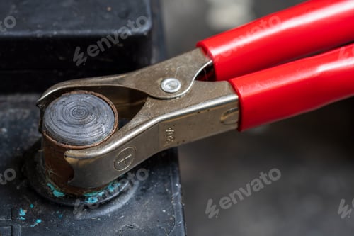 Preview: Close-up of red jumper cable clamp on car battery terminal.